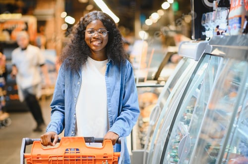 Preview: Beautiful African American woman making choice of products at supermarket