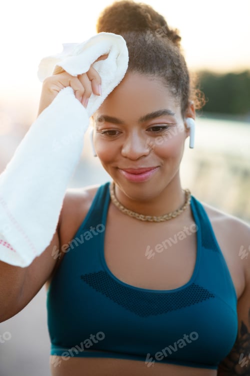 Preview: Young woman drying her sweat on forehead after intensive run