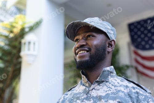 Preview: Portrait of african american male soldier standing in front of american flag outside home