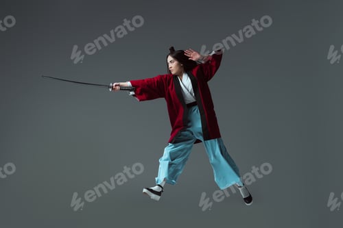 Preview: full length view of samurai in kimono fighting with katana in jump isolated on grey