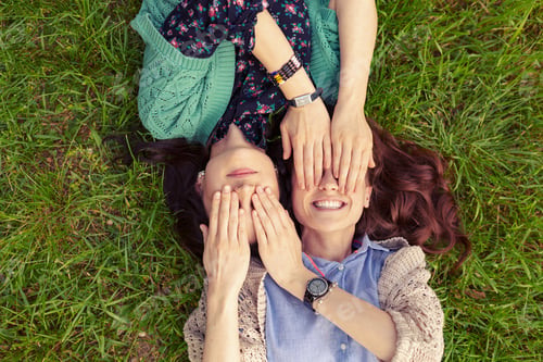 Preview: Top view of smiling friends lying on grass having fun