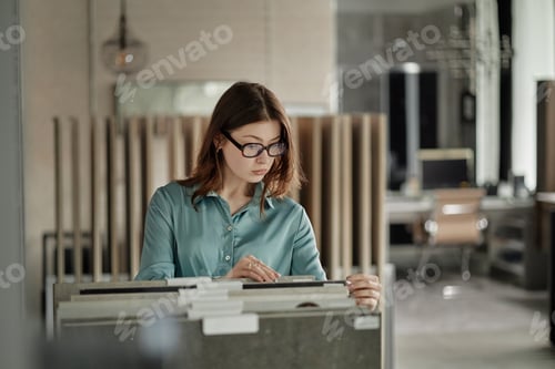 Preview: Young Caucasian Woman Wearing Glasses Searching Documents in Modern Office