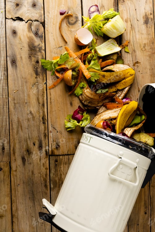 Preview: Vertical image of organic fruit and vegetable food waste spilling from open kitchen composting bin