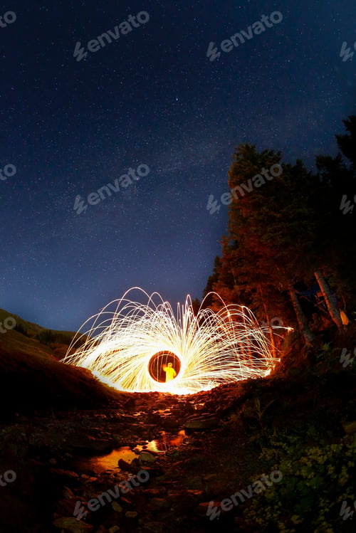 Preview: Person creating light trails with an orb in a long exposure shot