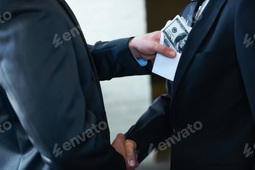 Preview: Two corporate businessmen shaking hands while one man places money in the otherampamp039s pocket