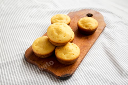Preview: Homemade Cornbread Muffins on a rustic wooden board, low angle view.