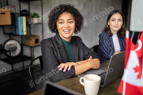 Preview: Black Businesswoman Sitting At Table Near European Colleague In Office