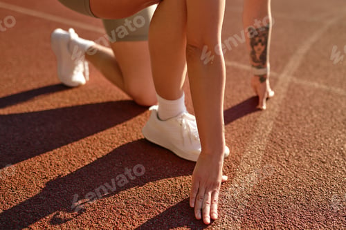 Preview: Female athlete in starting position on track