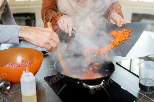 Preview: Hands of man mixing ingredients while female trainee adding chopped carrots