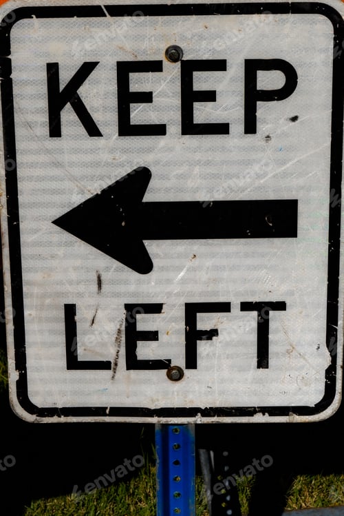 Preview: Vertical shot of a road sign of "Keep Left" with an arrow to the left
