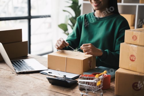Preview: Young woman packing product for customer with cardboard box at home, Business online shipping and de