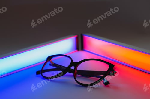 Preview: Stylish sunglasses shot using pink and blue abstract colored lighting with copy space.