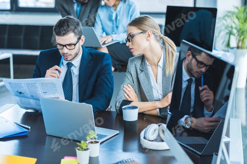 Preview: businessman and businesswoman looking at documents in office