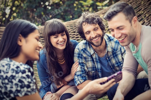 Preview: A group of friends lounging in a large hammock in the garden having a beer.