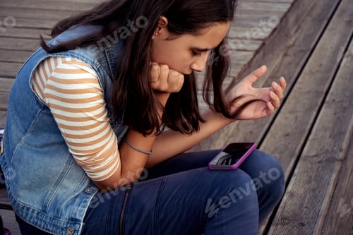 Preview: Girl sits on a park bench and texting on smartphones. Kid using technology People texting