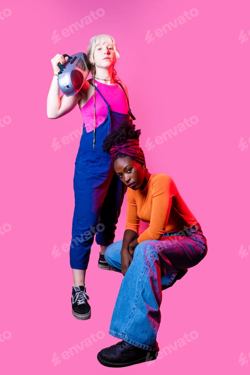 Preview: Two young diverse women holding boombox posing isolated confident