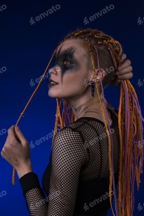 Preview: Cinematic portrait of woman with horror black stage make-up painted on face and dreadlocks hairstyle