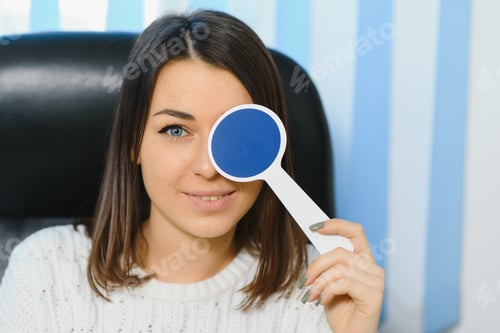 Preview: Young beautiful woman at the ophthalmologist's appointment checks her eyesight.