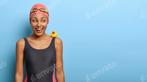 Preview: Funny joyous Afro American woman in bathing suit, enjoys spare time on favourite hobby, has training