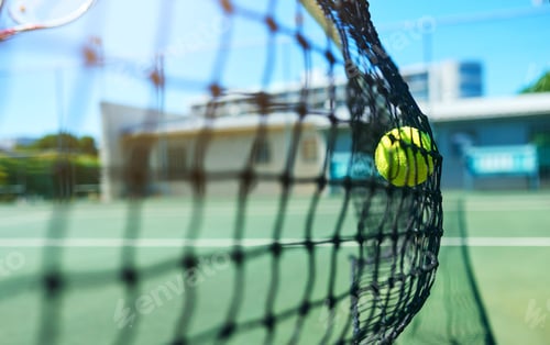 Preview: Cropped shot of a tennis ball hitting a tennis net on the court during the day