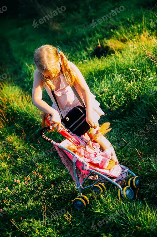 Preview: A happy little girl with a doll on a summer field.