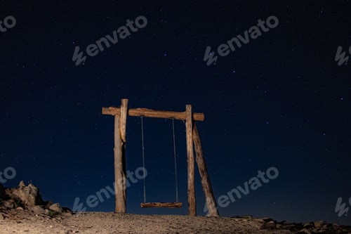 Preview: Outdoor swing set standing alone on a grassy hill, its empty seat creating a sense of loneliness