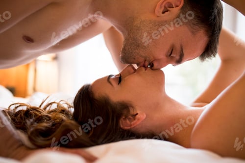 Preview: Romantic young couple laying on the bed with bodies in opposite directions while kissing