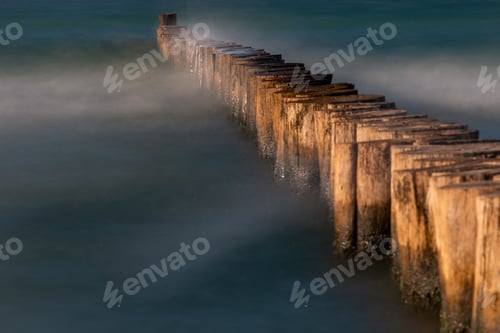 Preview: Closeup of wooden groins or breakwaters in the sea on a foggy day