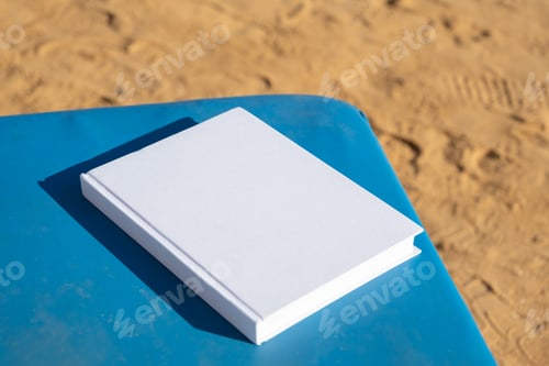 Preview: blank book mockup on lounge on sandy beach