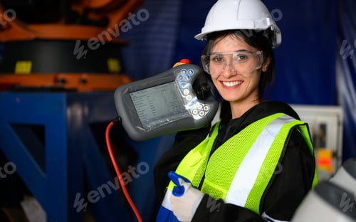 Preview: Female maintenance worker with machine robotic arms at industrial factory