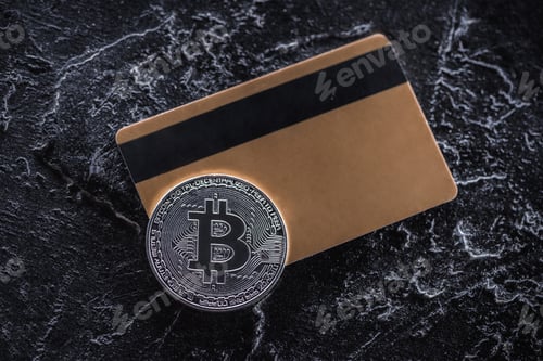Preview: top view of credit card and silver bitcoin on dark marble tabletop