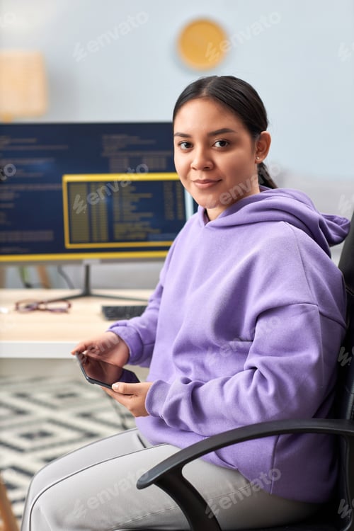 Preview: Young woman as computer programmer looking at camera at home office workplace