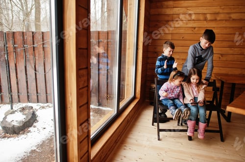 Preview: Children Together in Wooden Home Playing With Technology