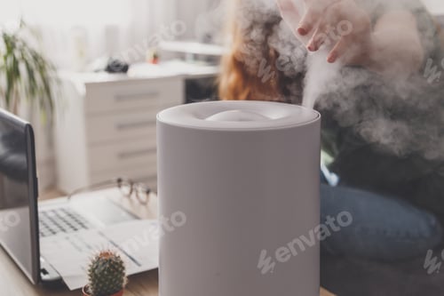 Preview: Woman freelancer uses a household humidifier in workplace