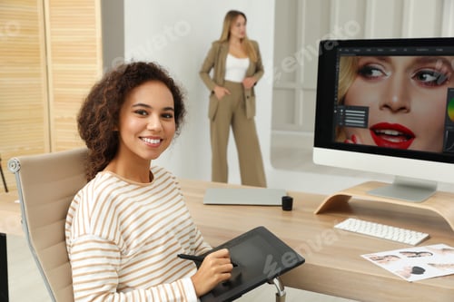 Preview: Professional African American retoucher working with graphic tablet at desk in photo studio