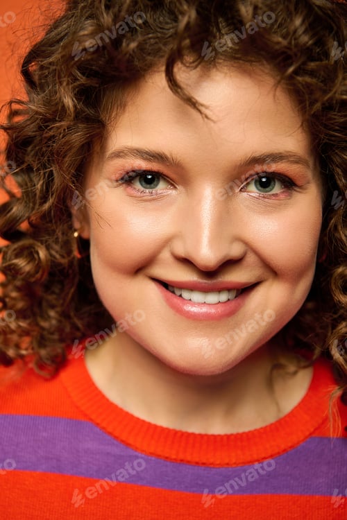 Preview: Curly girl smiles against orange
