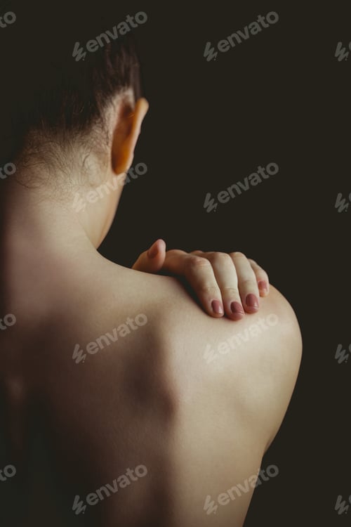Preview: Nude woman with a shoulder injury on black background
