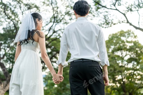 Preview: Asian young married couple holding hand each other in park during sunset.