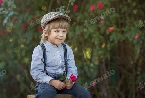 Preview: a little boy in vintage clothes walks near a rose bush