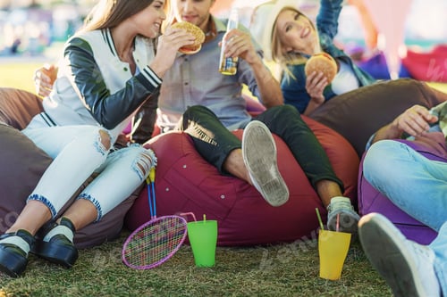 Preview: Colleagues Talking While Sitting On Poufs Together Outdoors