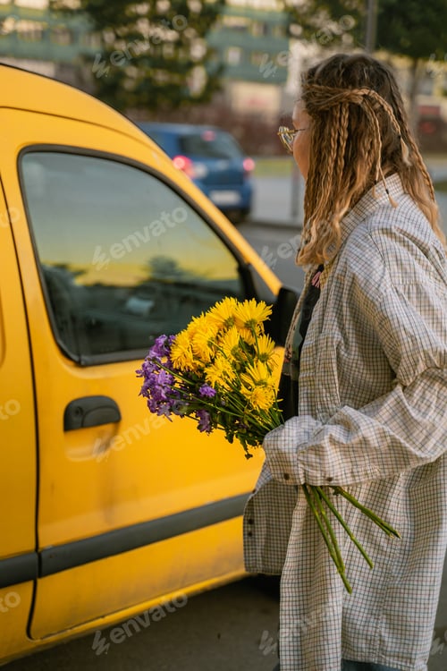 Preview: a girl with a bouquet of flowers goes to open the door in a yellow car