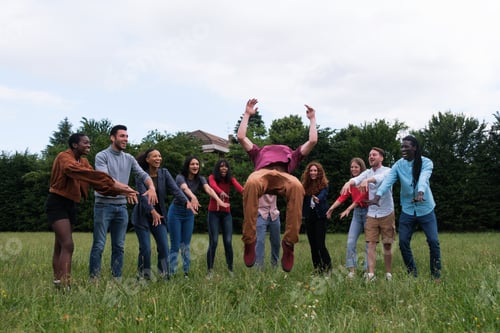 Preview: Young man doing a flip with his friends of different ethnicities supporting him