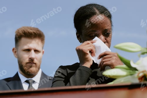 Preview: Young Black Woman Crying Beside Caucasian Man during Funeral Ceremony Outdoors