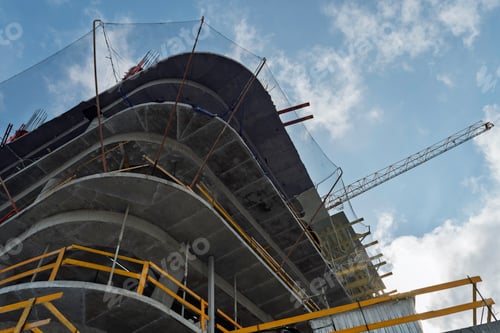 Preview: Layered concrete floors with safety nets and metal supports rise toward clouds