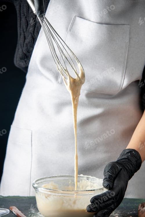 Preview: front view female cook in mask mixing up ingredients and making dough on dark background cuisine