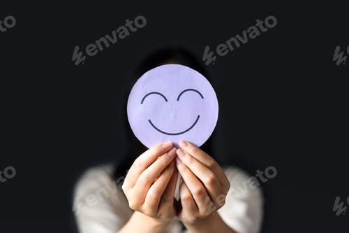 Preview: Happy Face Held Up Against Black Background