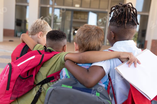 Preview: Rear view of multiracial elementary schoolboys with arm around standing at school campus