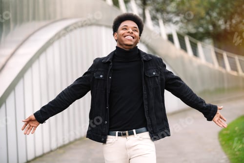 Preview: Moroccan man with afro hair with his arms open looking up very smiling and happy with street style