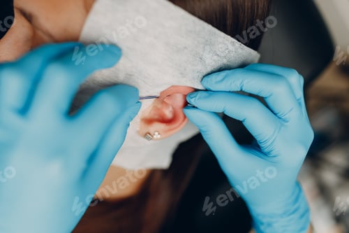 Preview: Young woman doing ear piercing at beauty studio salon.