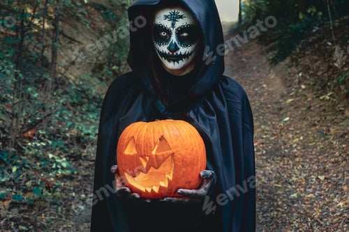 Preview: Young woman with halloween paint face mask wearing black hood